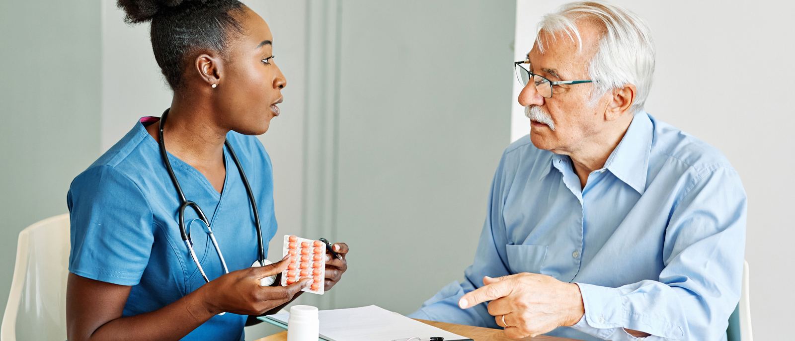 Nurse reviewing medications with an older man at home after he returns from the hospital