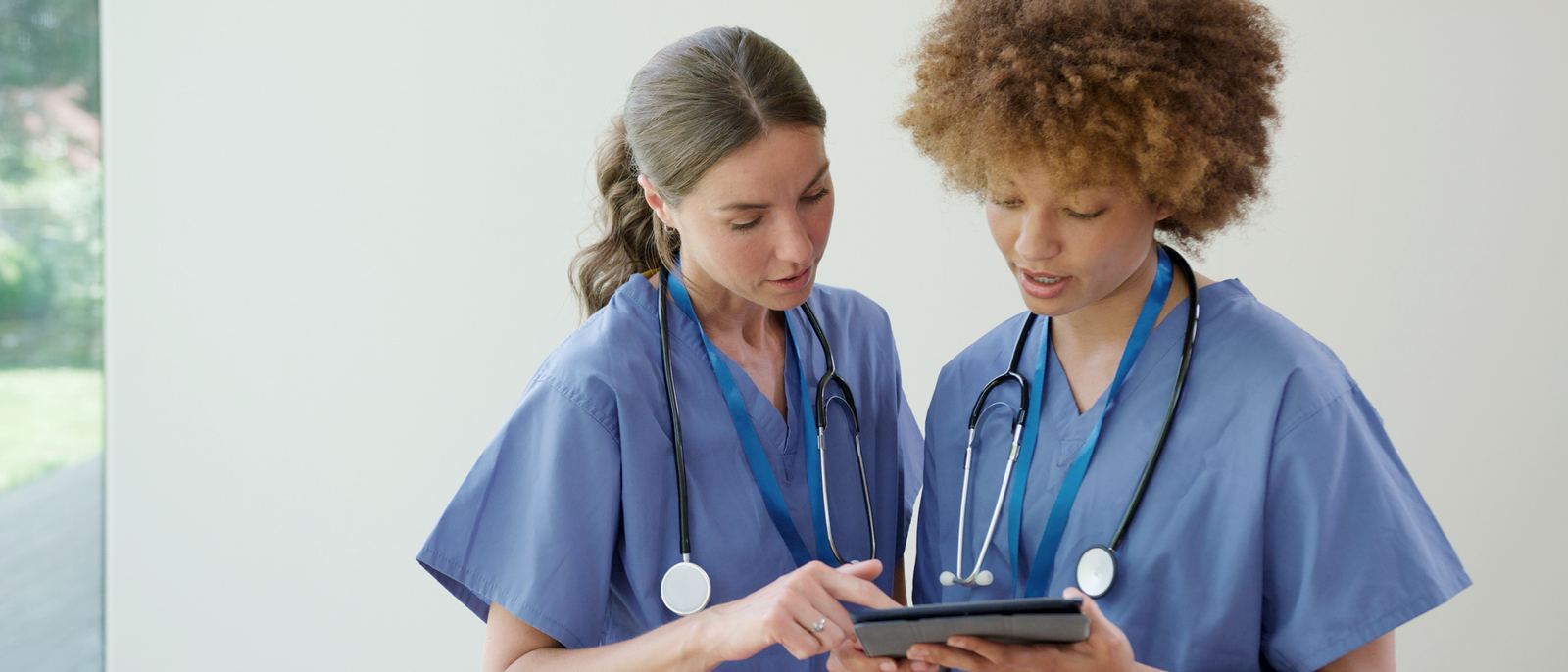 Two nurses reviewing patient care details together on a tablet