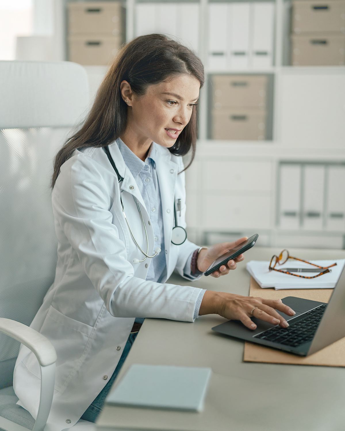 Clinician coordinating a home health referral by phone and laptop