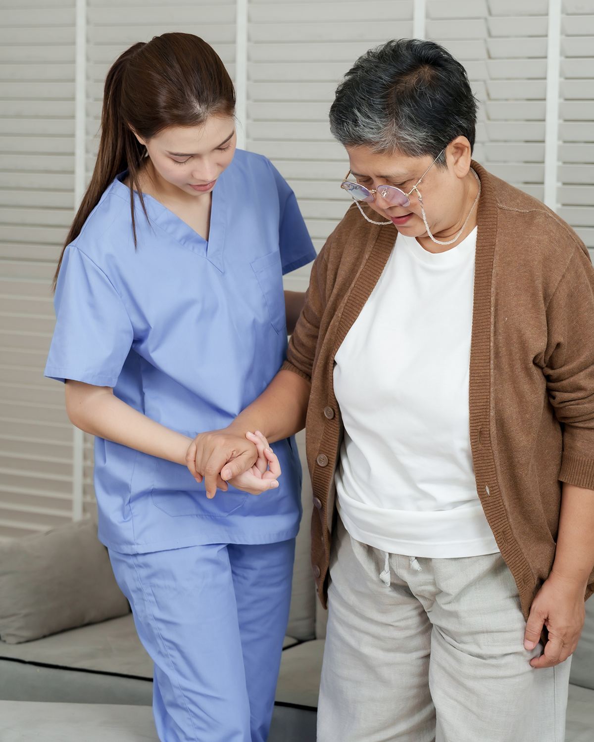 Nurse walking alongside an older woman at home as she regains her strength and independence